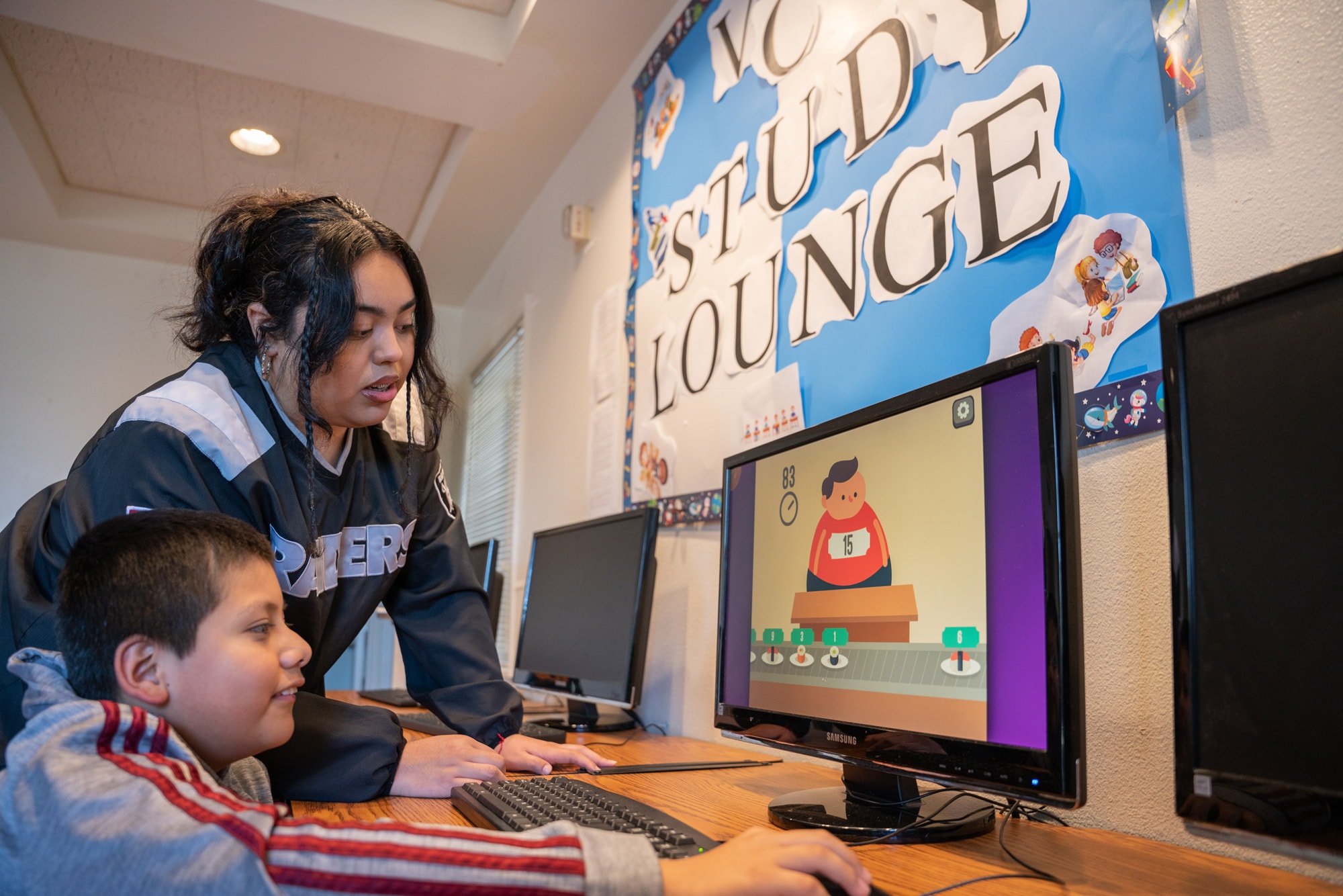 A photograph of a teacher and student working on a desktop computer in the VCH Study Lounge