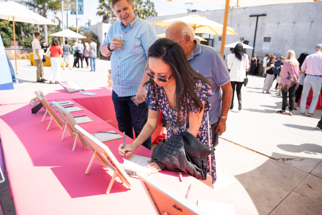 Woman writing on clipboard at Silent Auction table